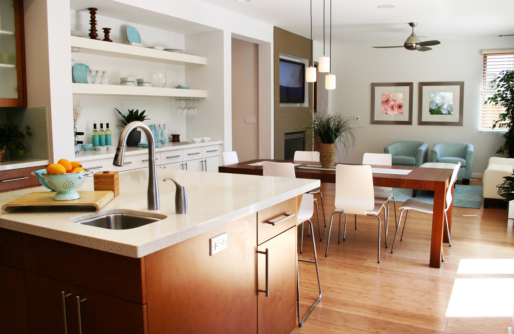 Modern open-plan kitchen and dining area with wood floors, white chairs around a wooden table, light blue and white decor, built-in shelves, and a small sitting area. Sash window repairs ensure natural light fills this stylish space.